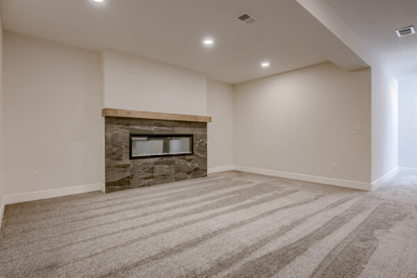 The Truman reverse 1.5-story floor plan lower level family room with gas fireplace by Patriot Homes.