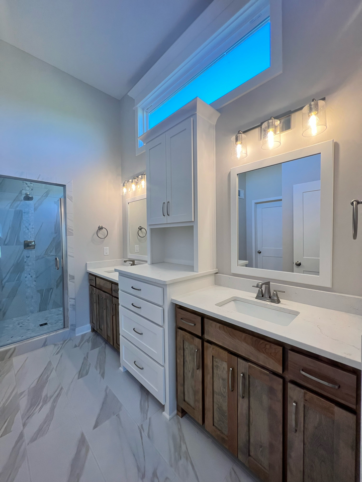 The Taft reverse 1.5-story floor plan master bathroom double vanity with stained and enameled painted white cabinets.