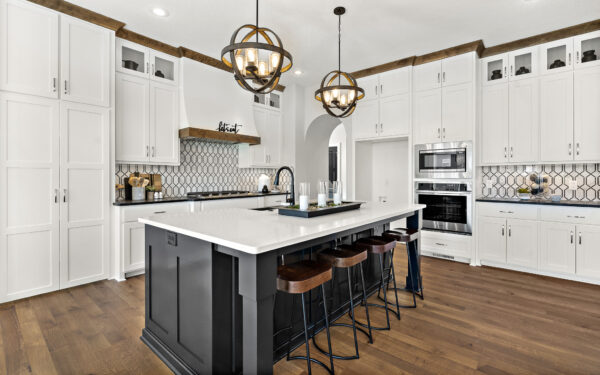 The Kennedy, a 2-story floor plan, kitchen features a large island with quartz counter top, gas cooktop, and white wood trimmed custom cabinets.